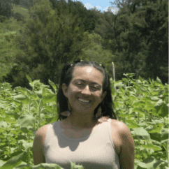 Amanda Calderón smiling at the camera in the middle of a corn field.